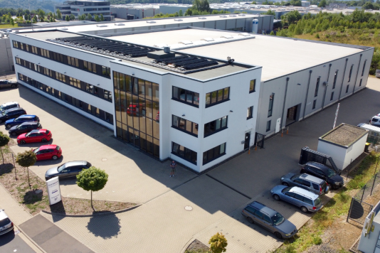 Luftaufnahme des Unternehmensstandorts von Baermann Magnettechnik mit modernem Bürogebäude, angrenzender Produktionshalle und Parkplätzen