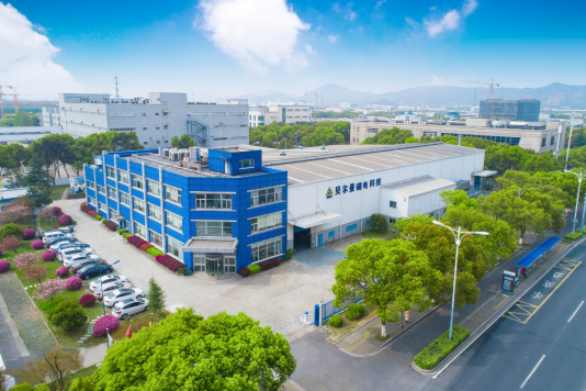 Luftaufnahme eines Produktionsstandorts in China mit blauem Bürogebäude, großer Produktionshalle und umliegendem Industriegebiet