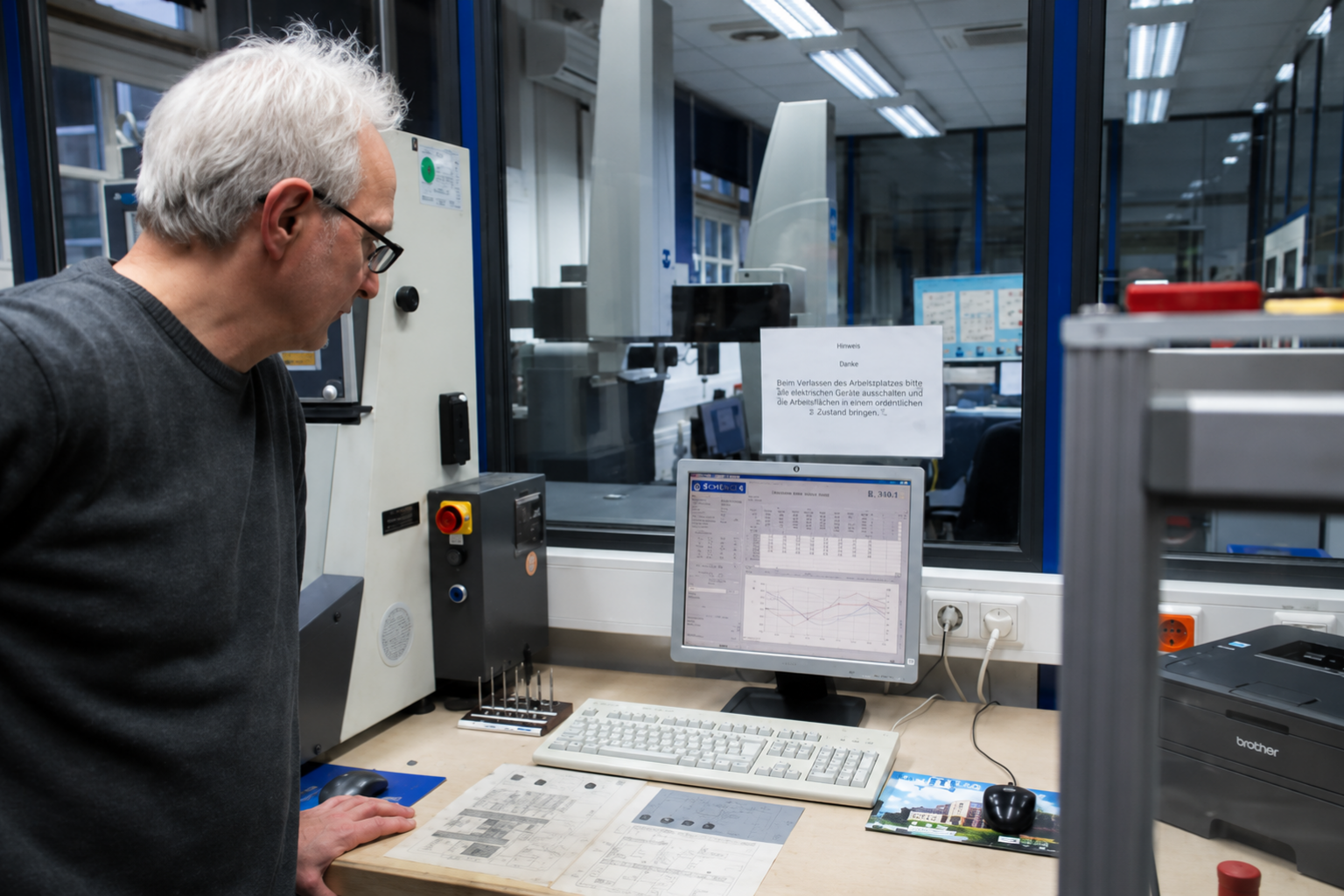 Mitarbeiter bei der Auswertung von Messdaten am Computer in einem industriellen Messraum zur Qualitätskontrolle