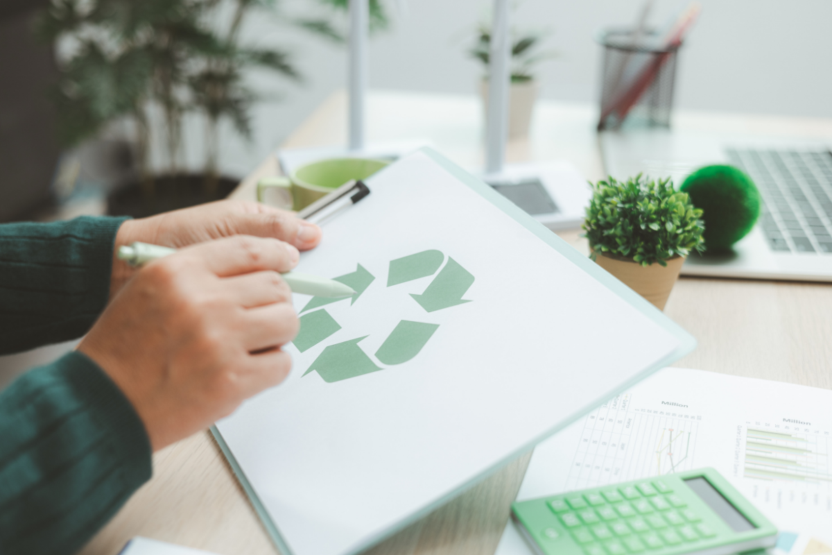 Person arbeitet mit Unterlagen zum Thema Recycling und Nachhaltigkeit an einem Schreibtisch