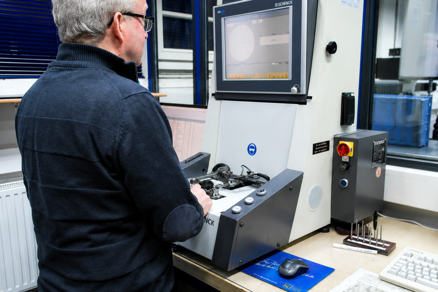 Mitarbeiter bei der Prüfung technischer Bauteile an einer Schenck-Messanlage im Qualitätslabor